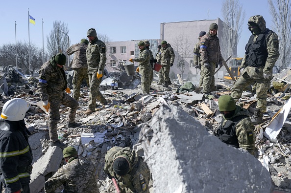 -Des soldats ukrainiens recherchent des corps dans les décombres de l'école militaire touchée par des roquettes russes la veille, à Mykolaïv, dans le sud de l'Ukraine, le 19 mars 2022. Photo de BULENT KILIC/AFP via Getty Images.