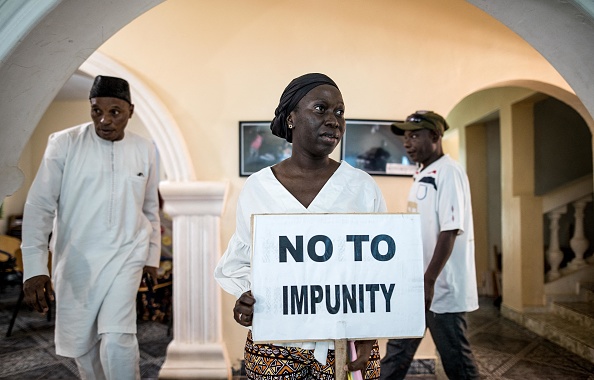 -Ayesha Hamun Jammeh, tient une pancarte de protestation qui dit, Non à l'impunité, en Gambie le 19 avril 2022. Photo de MUHAMADOU BITTAYE/AFP via Getty Images.