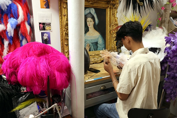 L'artiste népalais Susan Gurung, assistant de Dominique De Roo, plumassier officiel du cabaret du Lido, travaille les plumes utilisées pour les costumes, à l'intérieur de l'atelier, à Paris le 1er juin 2022. Photo de Thomas COEX / AFP via Getty Images.