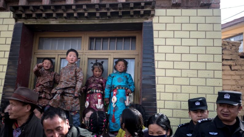 Enfants en vêtements traditionnels et policiers regardant passer les moines bouddhistes tibétains à l’occasion du Monlam, soit le grand festival de prières du Losar, le Nouvel An tibétain, au monastère de Rongwo, dans le comté de Tongren, dans la préfecture autonome tibétaine de Huangnan, sur le plateau du Qinghai-Tibet, le 1er mars 2018. (Johannes Eisele/AFP via Getty Images)