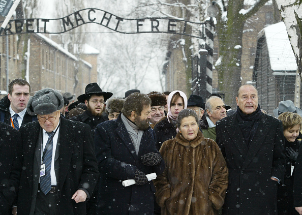 L'ancien président français, Jacques Chirac, avec l'ancienne prisonnière d'Auschwitz et ancienne ministre française de la Santé, Simone Veil, à l'entrée du camp de la mort nazi d'Auschwitz, le 27 janvier 2005.  (PATRICK KOVARIK/AFP via Getty Images) 