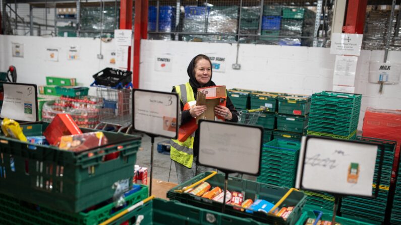 Une employée rassemble des denrées alimentaires dans des colis qui seront remis aux personnes ayant un bon de la banque alimentaire, à Coventry, Angleterre. (Photo : OLI SCARFF/AFP via Getty Images)