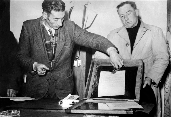 M. Faugeras, maire d'Oradour-sur-Glane retire solennellement de son écrin, le 20 février 1953, la Croix de Guerre que Max Lejeune, Secrétaire d'État aux Forces Armées, avait remis officiellement au village martyre le 10 juin 1948. (Photo : -/AFP via Getty Images)