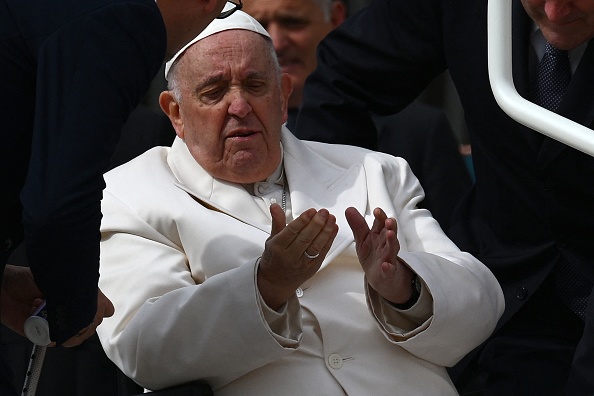 Le pape François s'entretient avec ses assistants avant d'être aidé à monter de son fauteuil roulant dans la popemobile, le 29 mars 2023, à la fin de l'audience générale hebdomadaire sur la place Saint-Pierre au Vatican. (VINCENZO PINTO/AFP via Getty Images)