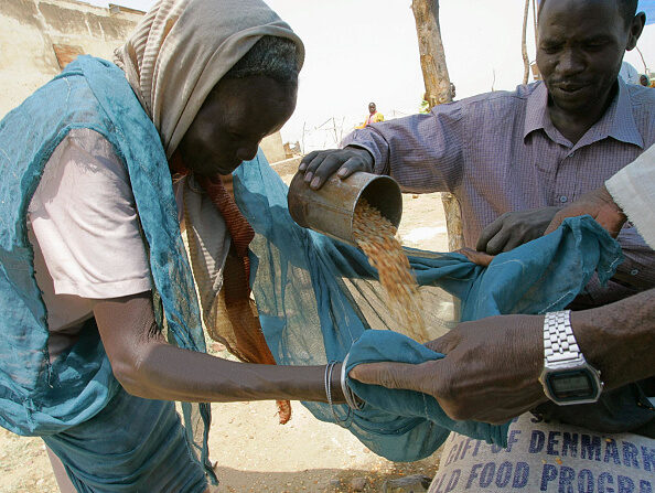 Une vieille femme soudanaise reçoit des céréales de la part d'employés du Programme alimentaire mondial des Nations unies. (CRIS BOURONCLE/AFP via Getty Images)