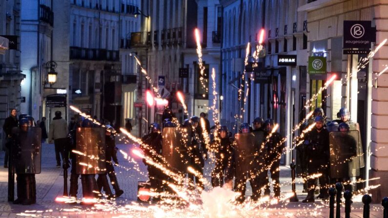 Des policiers se protègent des feux d'artifice lors d'une manifestation quelques jours après que le gouvernement français a fait passer une réforme des retraites au parlement sans vote, en utilisant l'article 49.3 de la constitution, à Nantes, dans l'ouest de la France, le 21 mars 2023. (Photo LOIC VENANCE/AFP via Getty Images)
