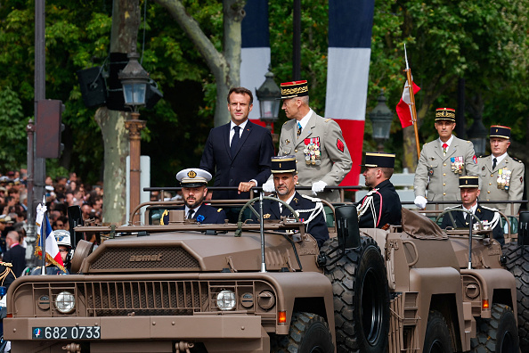 Le président français Emmanuel Macron et le chef d'état-major des armées Thierry Burkhard se tiennent dans la voiture de commandement lors du défilé militaire du Jour de la Bastille sur l'avenue des Champs-Élysées à Paris, le 14 juillet 2023.  (GONZALO FUENTES/POOL/AFP via Getty Images)