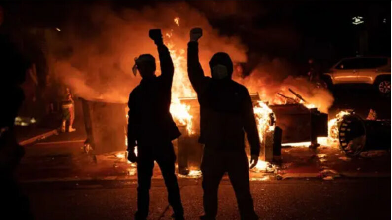 Des manifestants lèvent le poing alors qu'un feu brûle après des affrontements avec les forces de l'ordre près du commissariat de police de Seattle (East Precinct), le 8 juin 2020. Les manifestations ont été déclenchées par la mort de George Floyd, arrêté par la police. (David Ryder/Getty Images)