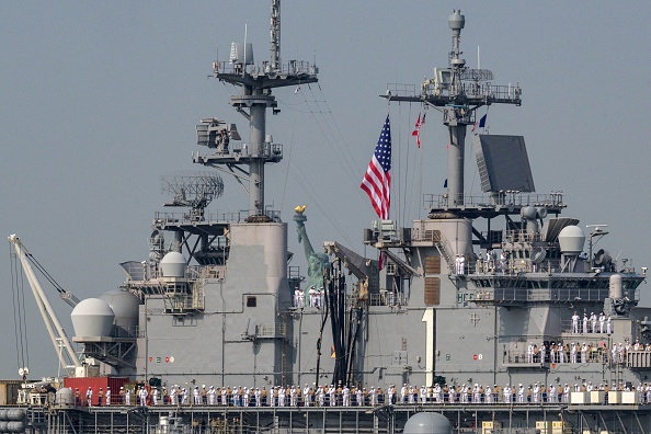 Des marins américains se tiennent sur le pont d'envol de l'USS Bataan, un navire d'assaut amphibie de classe Wasp. (Photo ANGELA WEISS/AFP via Getty Images)