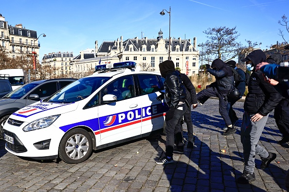 Un manifestant donne un coup de pied à une voiture de police sur la Place d'Italie à Paris le 12 février 2022. Illustration. (Photo SAMEER AL-DOUMY/AFP via Getty Images)