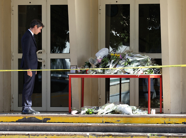 Le ministre de l'Éducation Gabriel Attal à côté de fleurs déposées devant le lycée Gambetta à Arras où un enseignant a été tué lors d'une attaque au couteau, le 14 octobre 2023. (Photo DENIS CHARLET/AFP via Getty Images)
