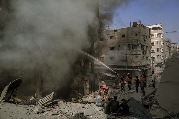 Des pompiers éteignent un bâtiment englouti par le feu et la fumée suite aux frappes aériennes israéliennes qui ont frappé Gaza, le 23 octobre 2023. (Photo MOHAMMED ZAANOUN/Middle East Images/AFP via Getty Images)