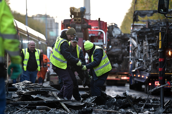 Des ouvriers nettoient les débris d'un train et de véhicules incendiés le 24 novembre 2023 à Dublin, en Irlande. (Photo Charles McQuillan/Getty Images)