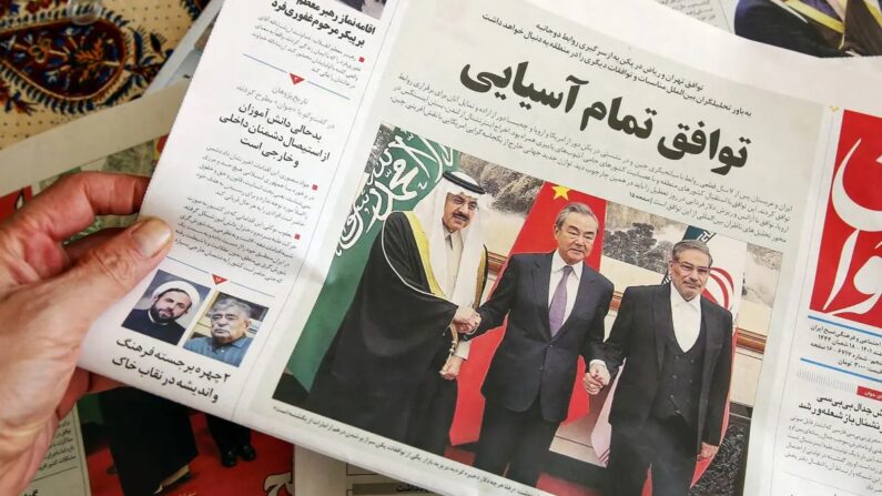 Un homme à Téhéran tient un journal local avec en première page un article sur l'accord négocié par la Chine entre l'Iran et l'Arabie Saoudite pour rétablir leurs relations, signé à Pékin le jour précédent, le 11 mars 2023. (ATTA KENARE/AFP via Getty Images)