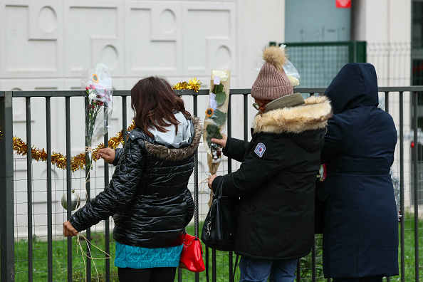 Des personnes déposent des fleurs devant l'appartement du rez-de-chaussée où les corps d'une femme, Béatrice, et de ses quatre enfants ont été découverts, à Meaux, dans l'est de Paris, le 26 décembre 2023. (Photo ALAIN JOCARD/AFP via Getty Images)
