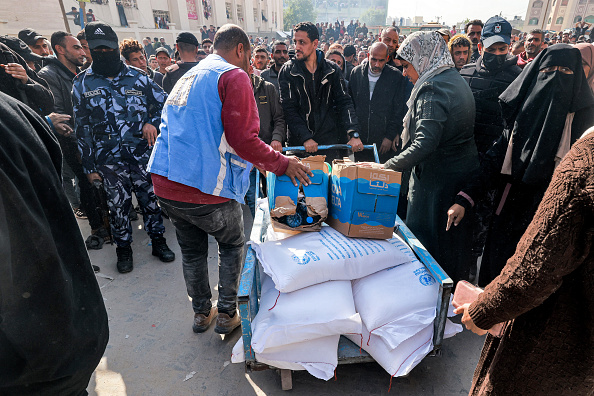 Des travailleurs de l'Office de secours et de travaux des Nations Unies pour les réfugiés de Palestine (UNRWA) distribuent des rations de farine et d'autres fournitures à des personnes dans un entrepôt de l'UNRWA à Rafah. (Photo MOHAMMED ABED/AFP via Getty Images)