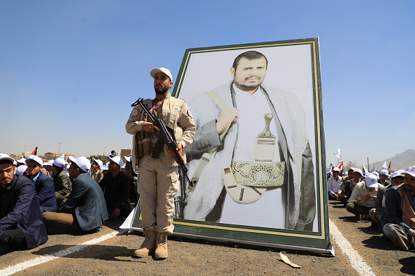 Un garde de sécurité huthi se tient devant un portrait du chef du groupe yéménite, Abdul Malik al-Huthi. (Photo MOHAMMED HUWAIS/AFP via Getty Images)