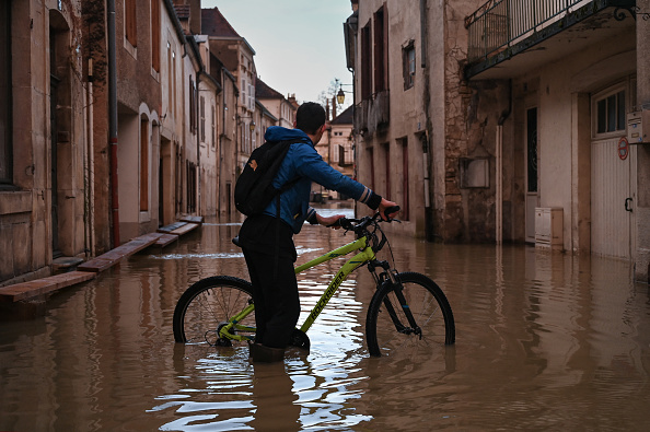 Cette photographie prise à Montbard, le 1er avril 2024, montre un habitant à vélo dans une rue inondée. (Photo ARNAUD FINISTRE/AFP via Getty Images)