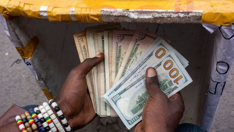 Un cambiste compte les billets dans sa cabine sur un marché de Kinshasa, le 11 août 2021. (ARSENE MPIANA/AFP via Getty Images)