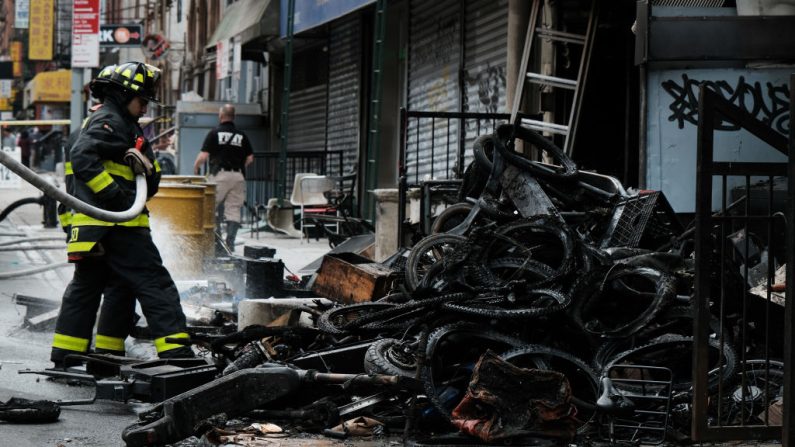Des pompiers travaillent à l'extérieur d'un bâtiment dans le quartier chinois où quatre personnes ont trouvé la mort dans l'incendie d'un atelier de réparation de vélos électriques, le 20 juin 2023 à New York. (Spencer Platt/Getty Images)