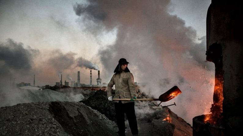 Un ouvrier chinois charge du charbon dans un four alors que de la fumée et de la vapeur s'élèvent d'une usine d'acier non autorisée en Mongolie intérieure, Chine, le 3 novembre 2016. (Kevin Frayer/Getty Images)