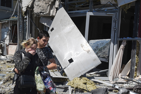 Des résidents locaux sont vus devant le bâtiment endommagé à la suite d'une frappe à Donetsk, ville d'Ukraine contrôlée par la Russie, le 11 mai 2024. (Photo STRINGER/AFP via Getty Images)