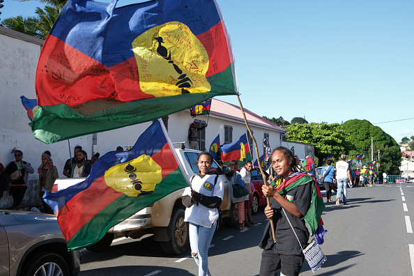 Des manifestants brandissent des drapeaux du Front de libération nationale kanak socialiste (FLNKS) alors qu'ils participent à un rassemblement organisé par la Cellule de coordination de terrain (CCAT) devant le palais de justice de Nouméa, le 13 mai 2024. (Photo THEO ROUBY/AFP via Getty Images)