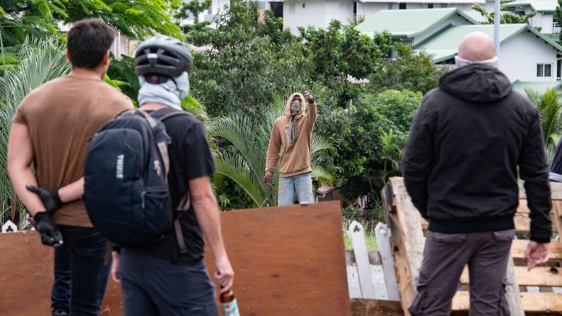 Des résidents masqués observent un activiste à l'entrée de Tuband, dans le quartier de Motor Pool à Nouméa, le 15 mai 2024. (DELPHINE MAYEUR/AFP via Getty Images)