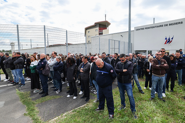 Des agents pénitentiaires observent une minute de silence alors qu'ils se rassemblent et bloquent l'entrée de la prison lors d'une manifestation à Béziers, le 15 mai 2024. (Photo PASCAL GUYOT/AFP via Getty Images)