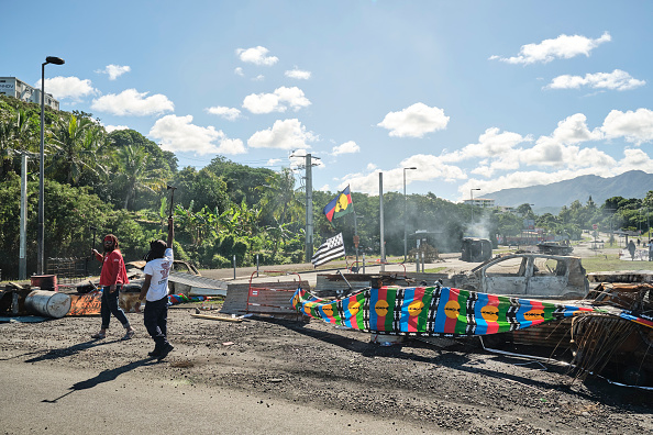 Des personnes tiennent un barrage routier, avec des drapeaux kanaks, contrôlant l'accès à un quartier de Nouméa, en Nouvelle-Calédonie, le 24 mai 2024. (Photo THEO ROUBY/AFP via Getty Images)