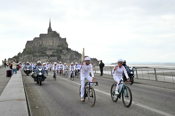 Le 31 mai 2024, le porteur de la flamme olympique passe à vélo devant le Mont-Saint-Michel. (Photo MIGUEL MEDINA/AFP via Getty Images)