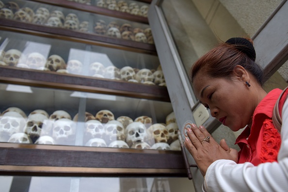 Une femme prie devant des crânes au mémorial de Choeung Ek à Phnom Penh.  (Photo credit should read TANG CHHIN SOTHY/AFP via Getty Images)
