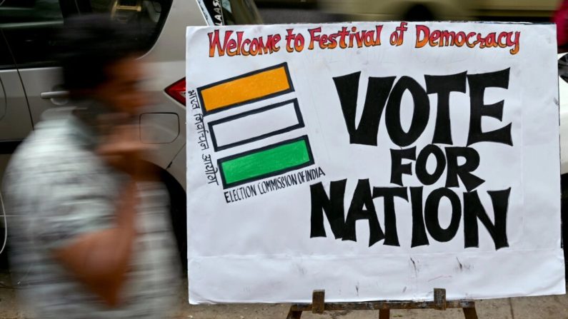 Un piéton passe devant une peinture sur le thème des élections placée par des étudiants en art le long d'une rue à l'extérieur de leur classe pour encourager les gens à voter lors des prochaines élections générales en Inde, à Mumbai, le 17 avril 2024. (Indranil Mukherjee / AFP via Getty Images)