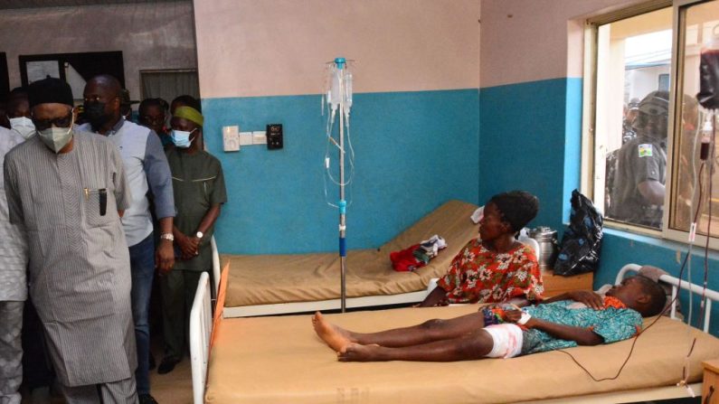 Des représentants de l'État passent devant des blessés soignés sur des lits d'hôpital après l'attaque par des hommes armés de l'église catholique Saint-François dans la ville d'Owo, dans le sud-ouest du Nigeria, le 5 juin 2022. (AFP via Getty Images)
