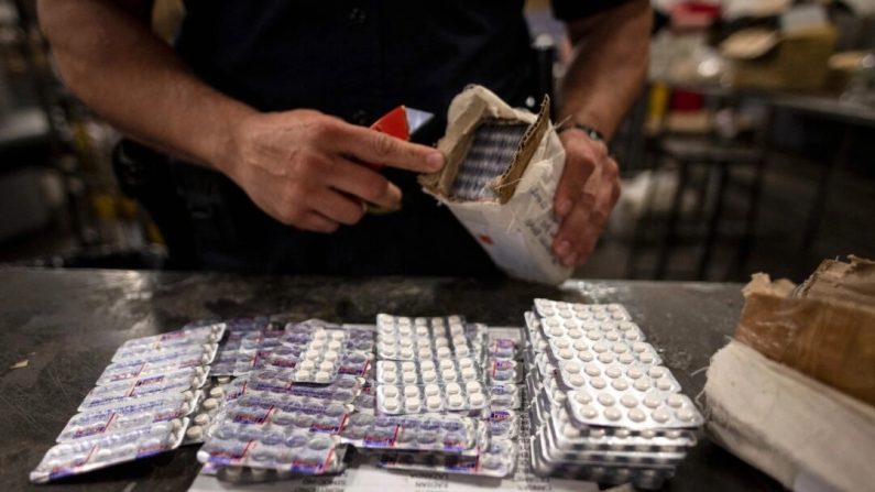 Un agent de la division du commerce et du fret des douanes et de la protection des frontières des États-Unis trouve des pilules d'oxycodone dans un colis à l'aéroport John F. Kennedy, à New York, le 24 juin 2019. (Johannes Eisele/AFP via Getty Images)