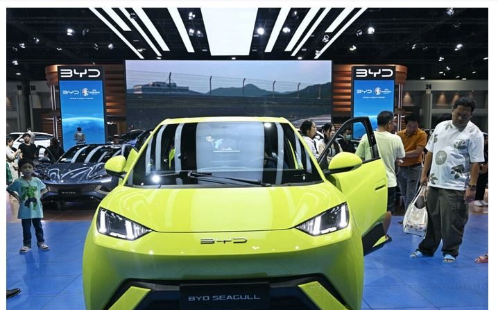 Des gens regardent une voiture électrique Seagull du fabricant chinois BYD Auto au salon international de l'automobile de Bangkok, le 27 mars 2024. (Lillian Suwanrumpha/AFP via Getty Images)