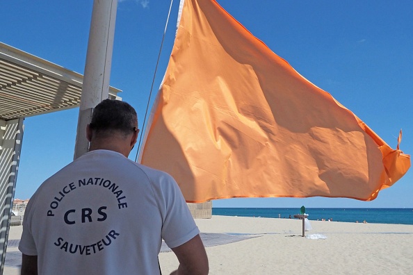 Un maître-nageur de la police française des CRS manipule un drapeau d'avertissement orange "baignade dangereuse" sur la plage de Port Barcarès (Pyrénées-Orientales).  (RAYMOND ROIG/AFP via Getty Images)