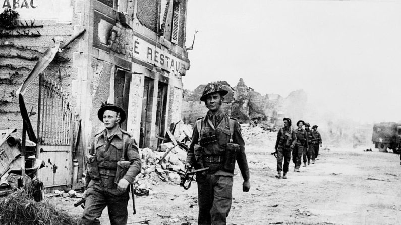 Des soldats britanniques traversent le 08 juin 1944 le village de Douet, après la chute de la ville de Bayeux, suite à l'assaut des plages normandes par les forces alliées. (Crédit photo STF/AFP via Getty Images)