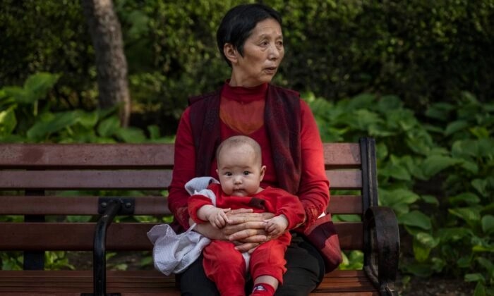 Une femme tient un bébé dans un parc de Pékin, en Chine, le 12 mai 2021. (Kevin Frayer/Getty Images)