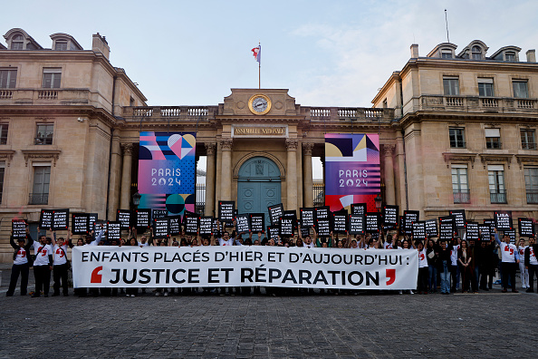 Un rassemblement d'anciens enfants placés, en hommage aux enfants placés décédés récemment dans le cadre de l'Aide sociale à l'enfance (ASE), à l'entrée de l'Assemblée nationale, à Paris, le 7 mai 2024. (LUDOVIC MARIN/AFP via Getty Images)