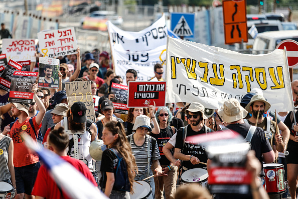 Des étudiants israéliens brandissent des images d'Israéliens kidnappés et des pancartes anti-guerre lors d'une manifestation devant la Knesset, le Parlement israélien, à Jérusalem. (SAEED QAQ/Middle East Images/AFP via Getty Images)