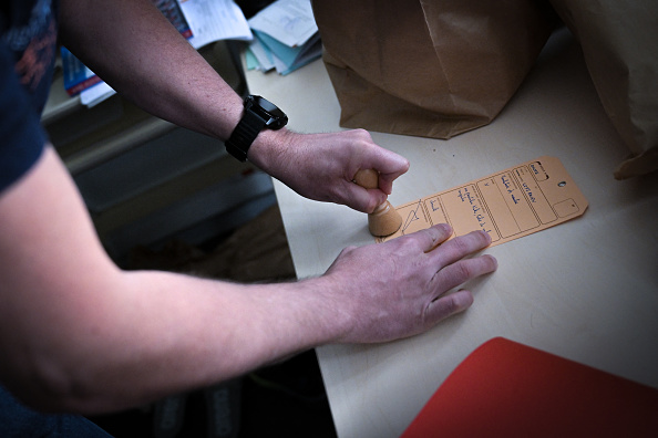 Un officier de police appose un tampon sur un papier d'enregistrement des scellés lors d'un exercice au Service Interdépartemental de la Police Judiciaire (SIPJ) à Rouen. (LOU BENOIST/AFP via Getty Images)