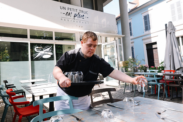 Tristan dresse les tables au restaurant « Un petit truc en plus » qui emploie des personnes trisomiques à Mulhouse, le 13 juin 2024. (Photo ABDESSLAM MIRDASS/AFP via Getty Images)