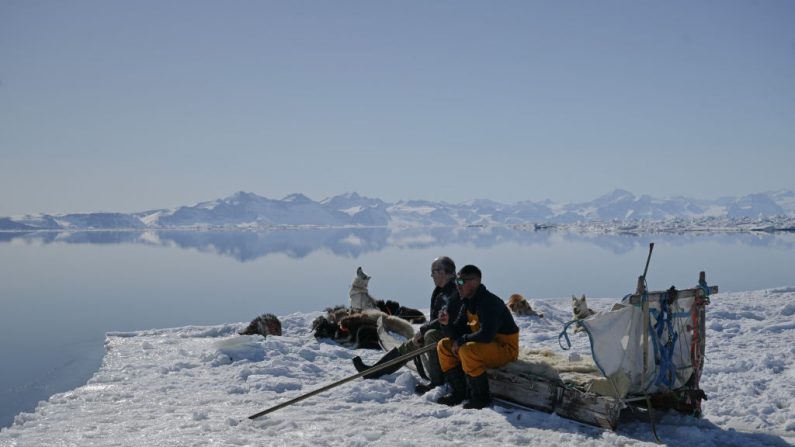 Le plus grand chasseur inuit d'ours polaires du Groenland, Hjelmer Hammeken (à g.), 66 ans, et Martin Madsen (à dr.) attendent les phoques à la lisière de la glace, assis sur un traîneau en bois, là où la glace de mer rencontre l'océan, à l'extérieur d'Ittoqqortoormiit, dans le fjord gelé de Scoresbysund, le 26 avril 2024. (Photo OLIVIER MORIN/AFP via Getty Images)