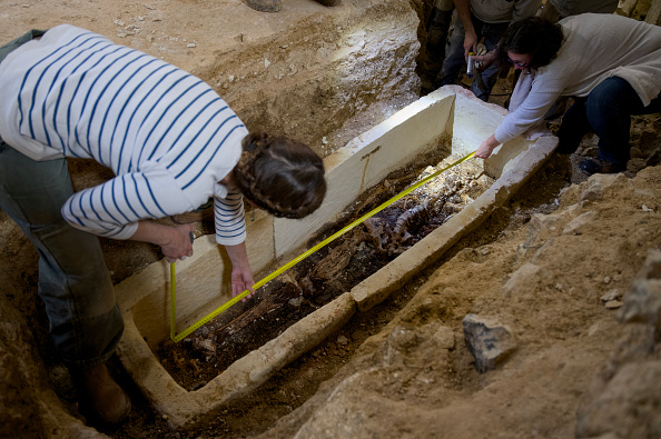 L'anthropologue Emilie Portal (à g.) prend la mesure du squelette contenu dans un sarcophage datant du VIe siècle après J.-C., de l'époque mérovingienne, après son ouverture, à l'intérieur de l'église Saint-Martin-au-Val, à Chartres, le 19 juin 2024. (GUILLAUME SOUVANT/AFP via Getty Images)