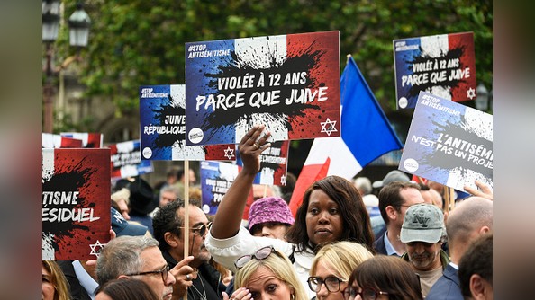 Des manifestants tiennent des pancartes sur lesquelles on peut lire "Violée parce que juive" lors d'un rassemblement pour condamner le viol collectif antisémite présumé d'une jeune fille de 12 ans à Courbevoie, lors d'un rassemblement à Paris le 19 juin 2024, suite à la mise en examen d'adolescents pour viol, menaces de mort, insultes antisémites et violences à son encontre. (Photo par MAGALI COHEN/Hans Lucas/AFP via Getty Images)