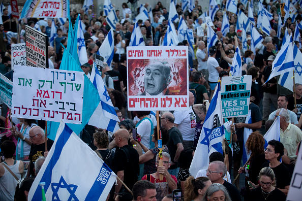 Des manifestants brandissent des pancartes et des drapeaux lors d'une manifestation réclamant un accord sur les otages et contre le Premier ministre israélien Benjamin Netanyahu et son gouvernement, le 22 juin 2024 à Tel Aviv, en Israël. (Amir Levy/Getty Images)