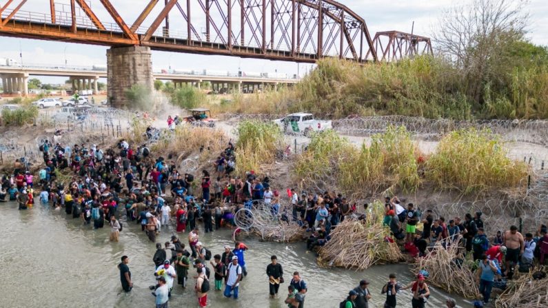 Des immigrés clandestins attendent dans le Rio Grande une ouverture dans la barrière de barbelés pour passer aux États-Unis, à Eagle Pass, au Texas, le 25 septembre 2023. (Andrew Caballero-Reynolds/AFP via Getty Images)