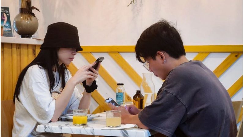 Un jeune couple est absorbé par son téléphone portable à Perth, en Australie-Occidentale, le 16 mars 2024. (Susan Mortimer/The Epoch Times)