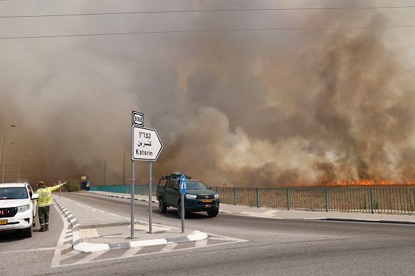 Des véhicules quittent une zone engloutie par la fumée des incendies après que des roquettes lancées par le Hezbollah depuis le Sud-Liban ont touché des zones du plateau du Golan, le 4 juillet 2024. (Photo JALAA MAREY/AFP via Getty Images)